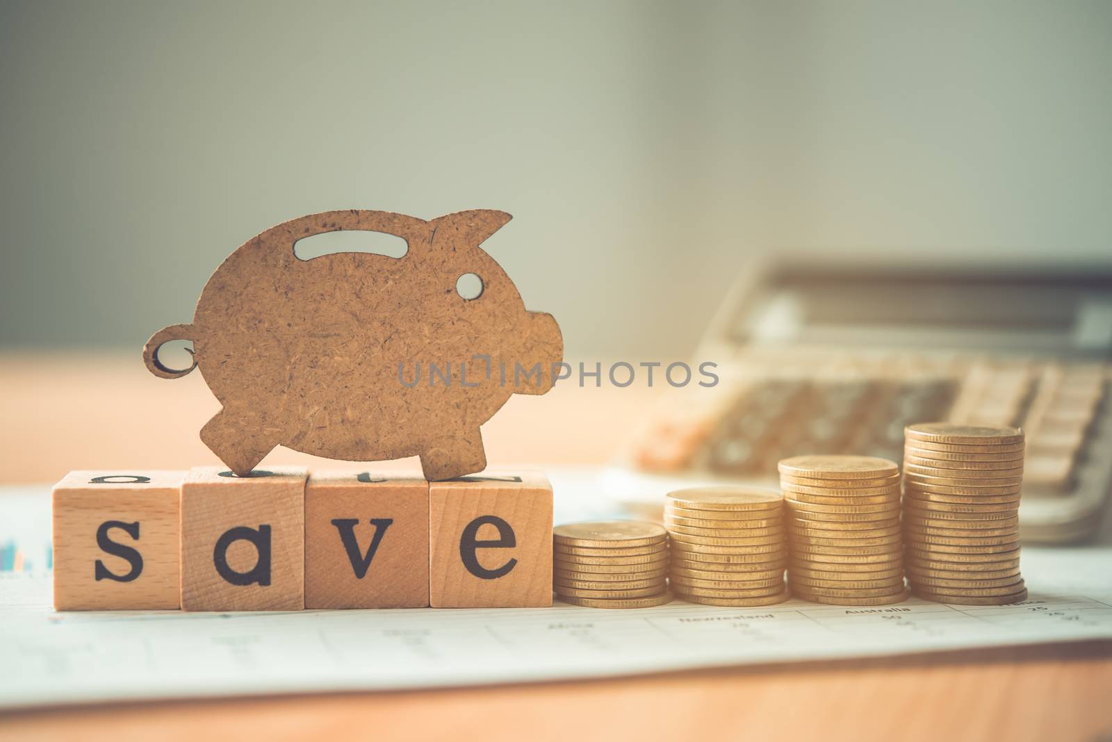The coins are stacked and wooden blocks are pig on the wooden floor. - Savings ideas for increasing volume.