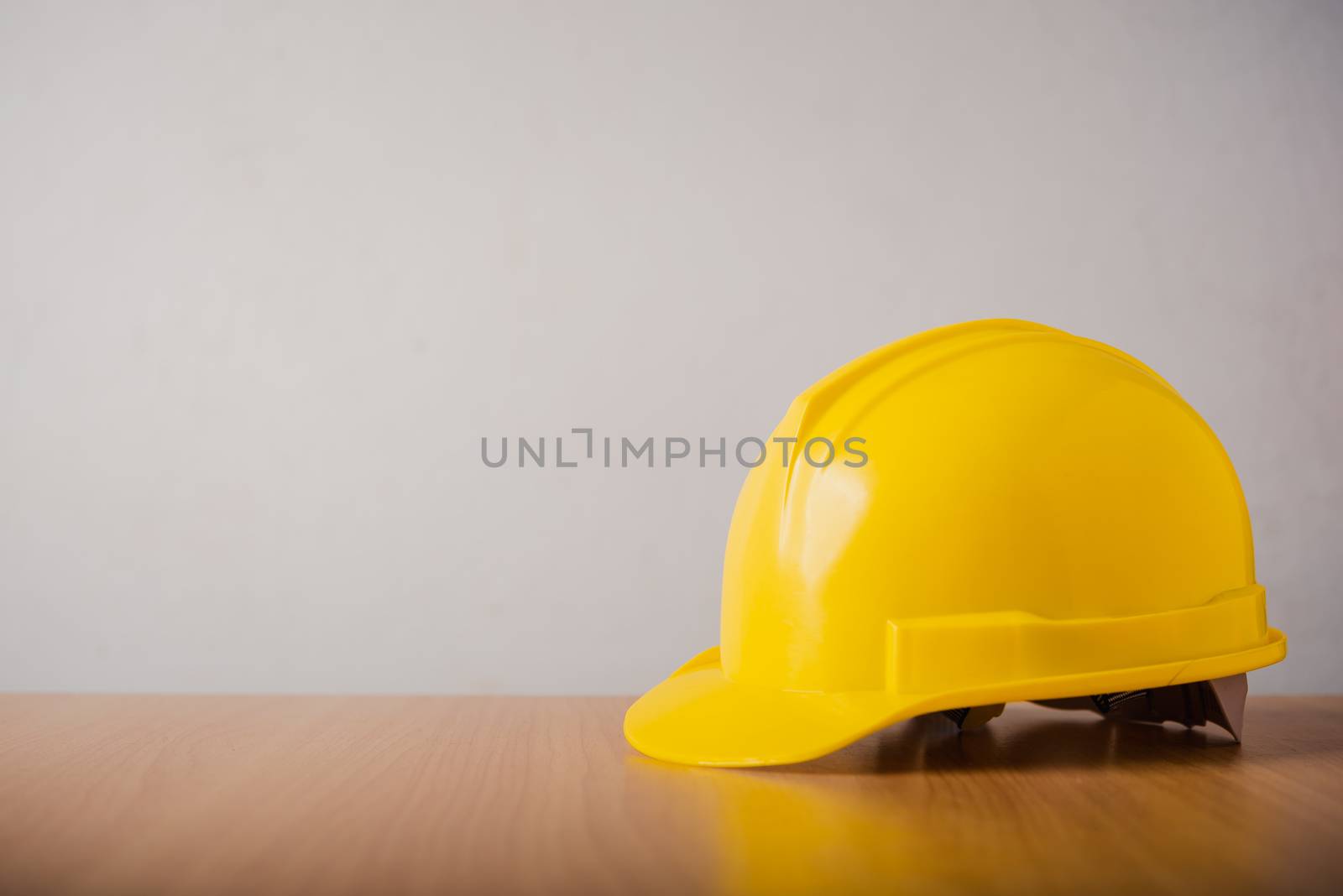 yellow hard hat safety helmet on wood background by photobyphotoboy
