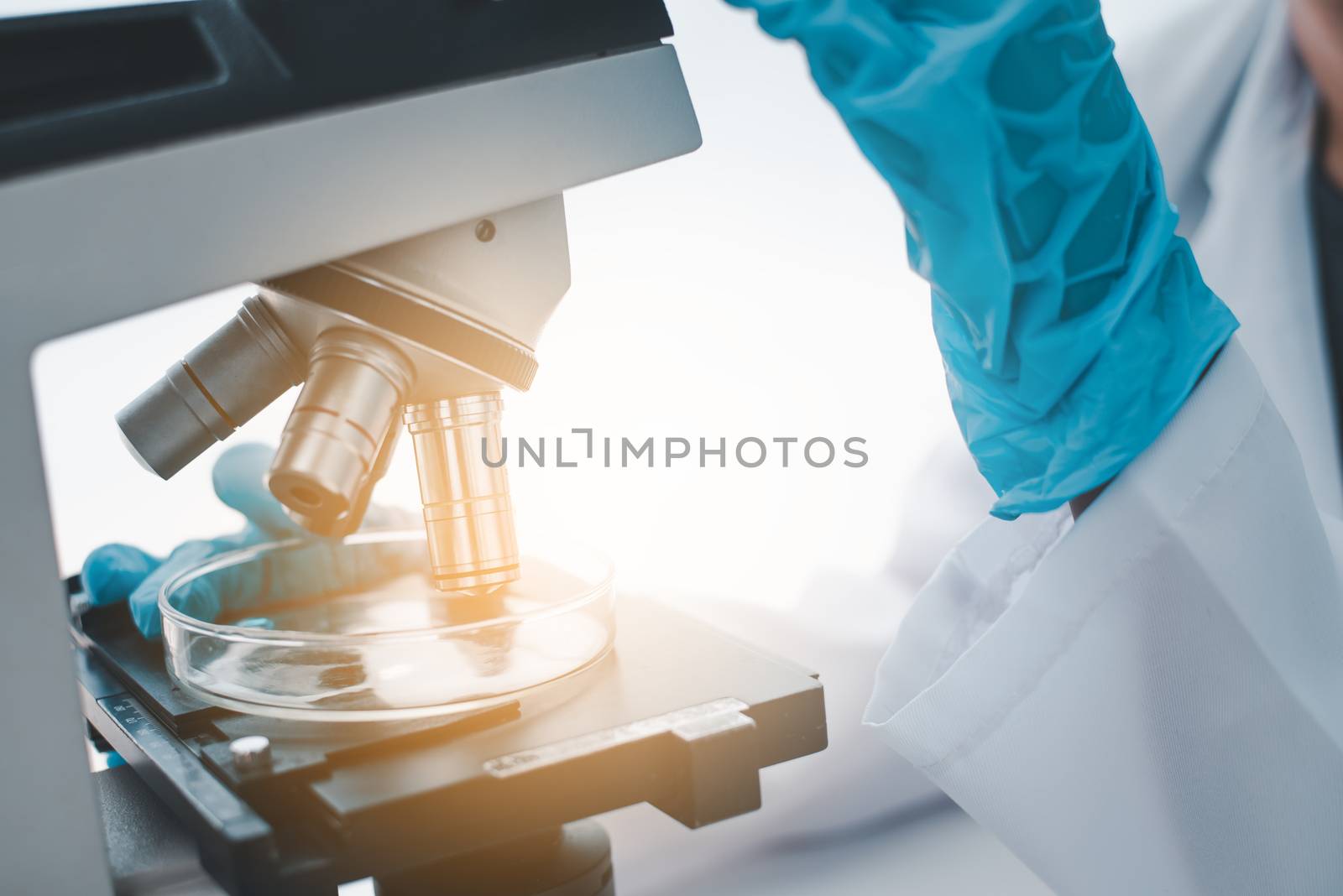 close-up female medical researcher looking at a microscope in a  by photobyphotoboy