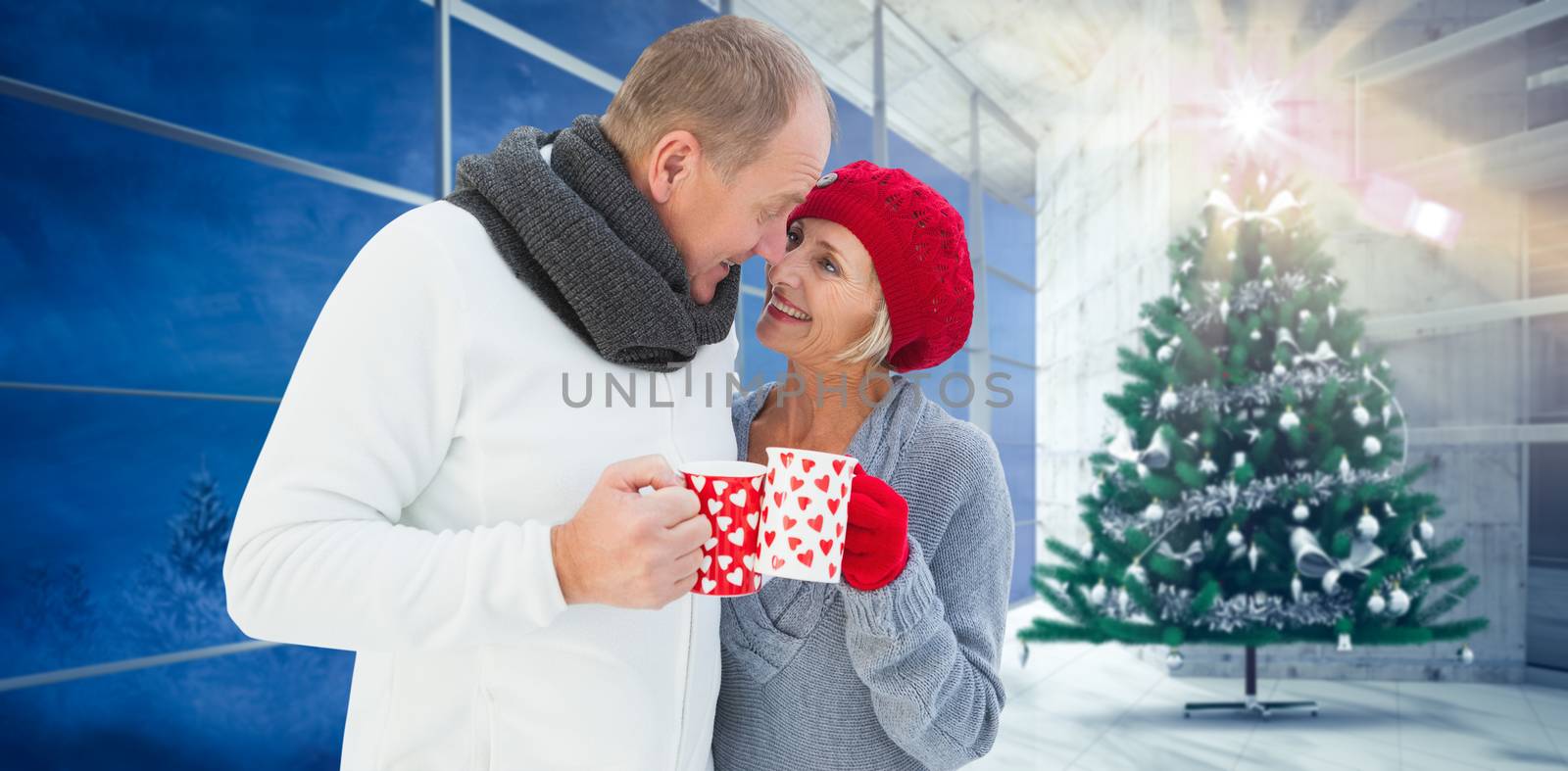 Mature couple holding mugs against home with christmas tree
