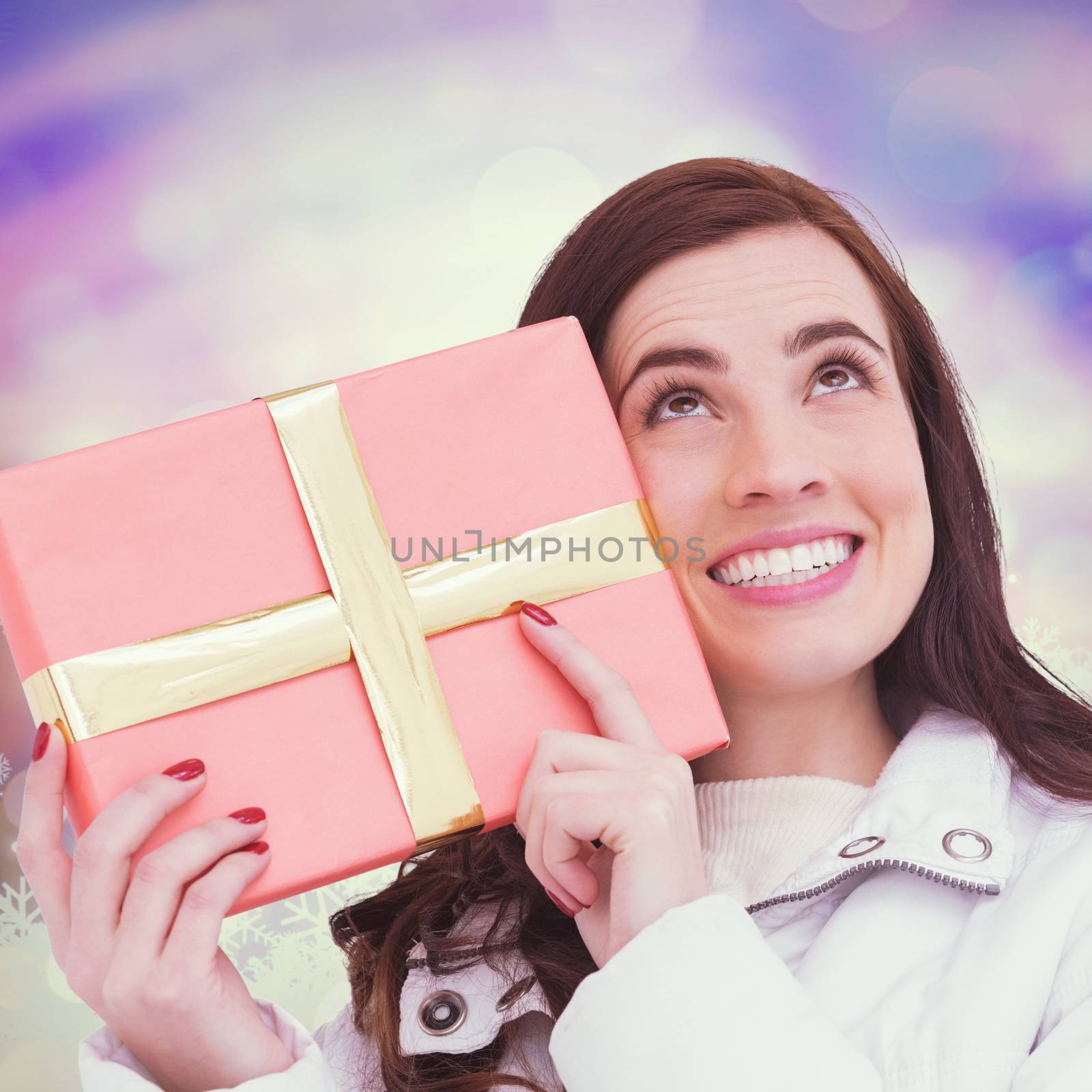 Portrait of a happy brunette holding gift  against glowing christmas background