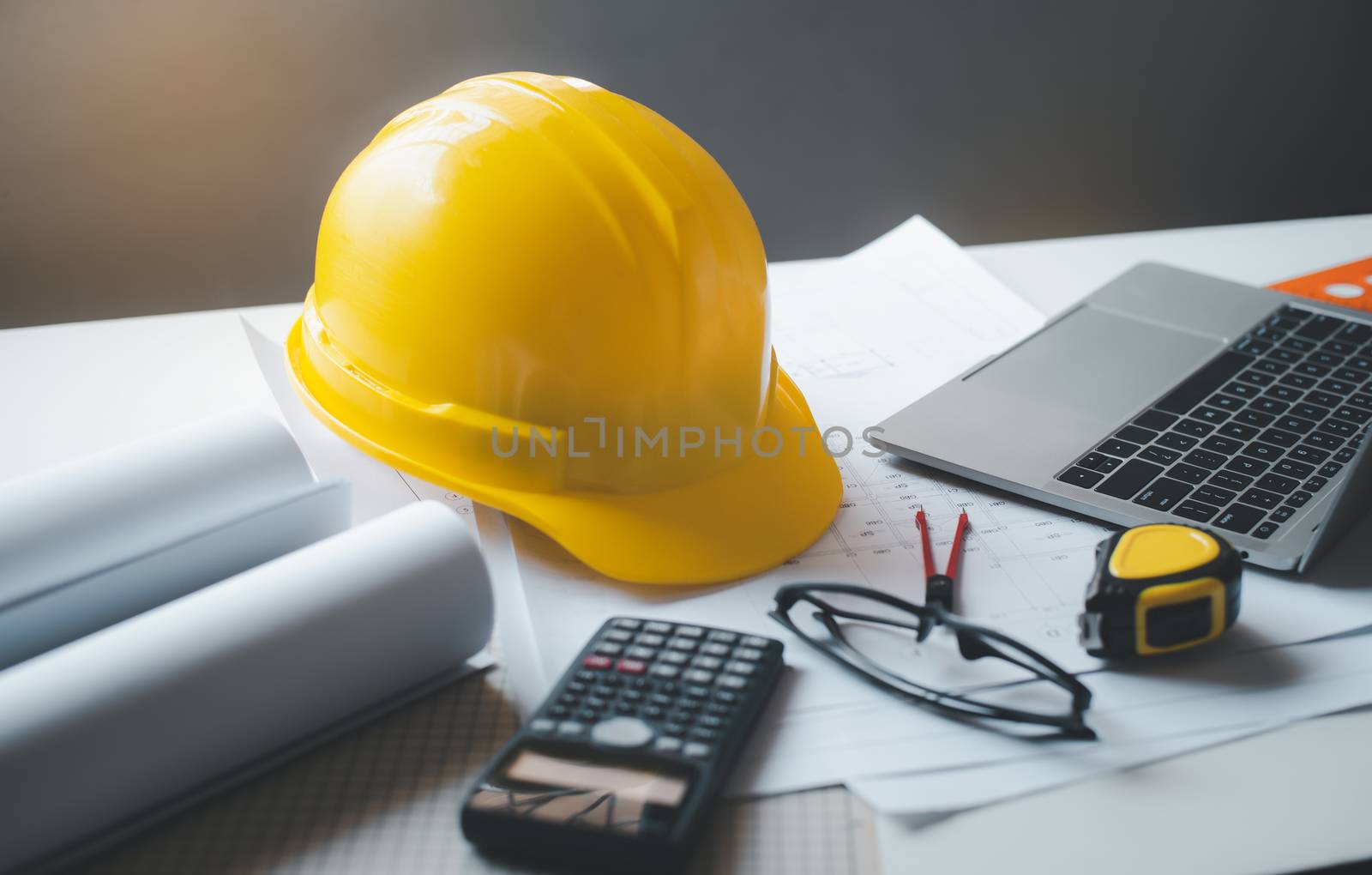 yellow hard hat safety helmet placed on a work desk with a desig by photobyphotoboy