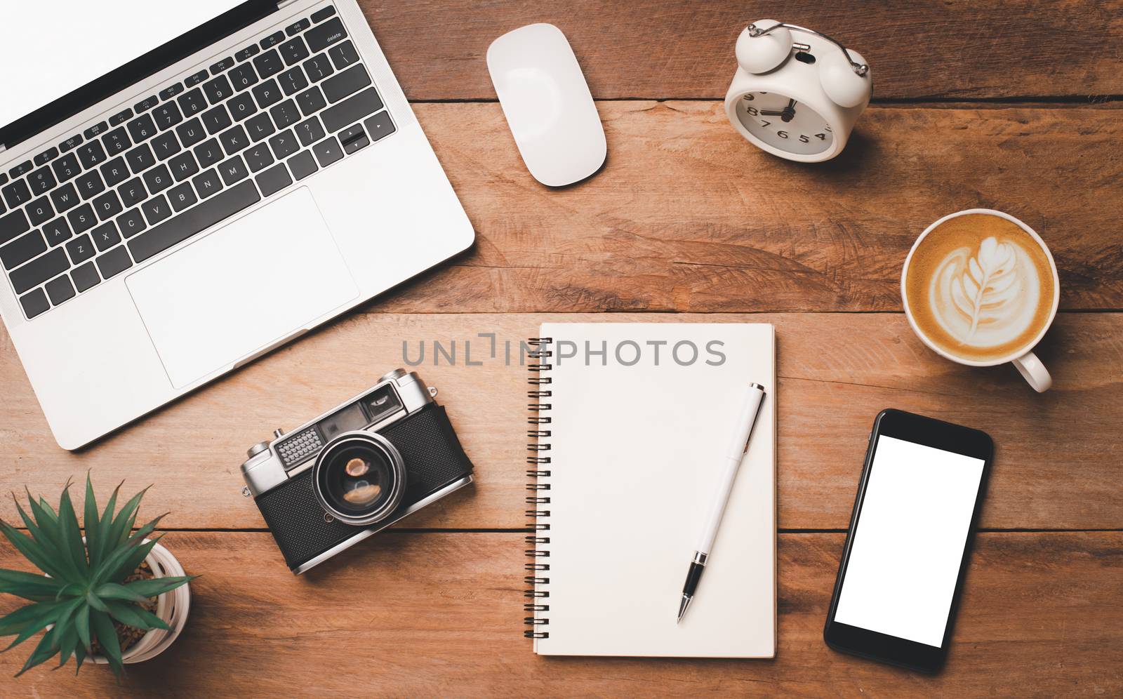 top view Office equipment including Laptop, mobile phone, mouse, notebook, coffee cup on the wood floor