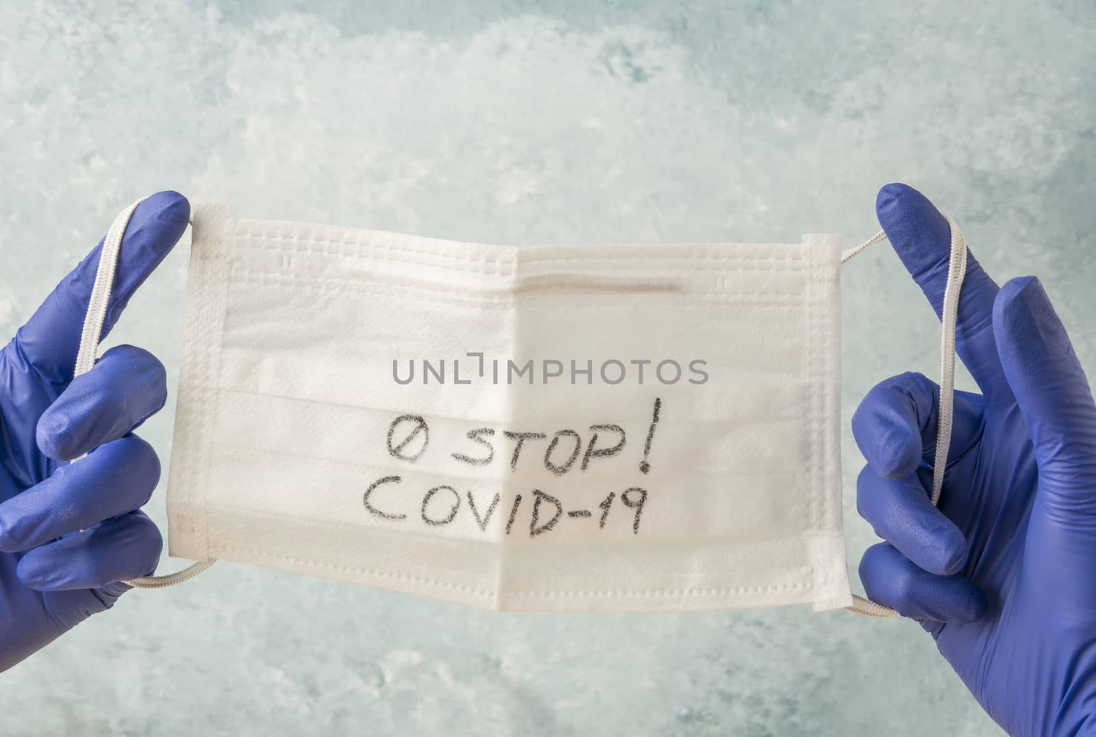 closeup hands with blue latex disposable gloves holding a health mask