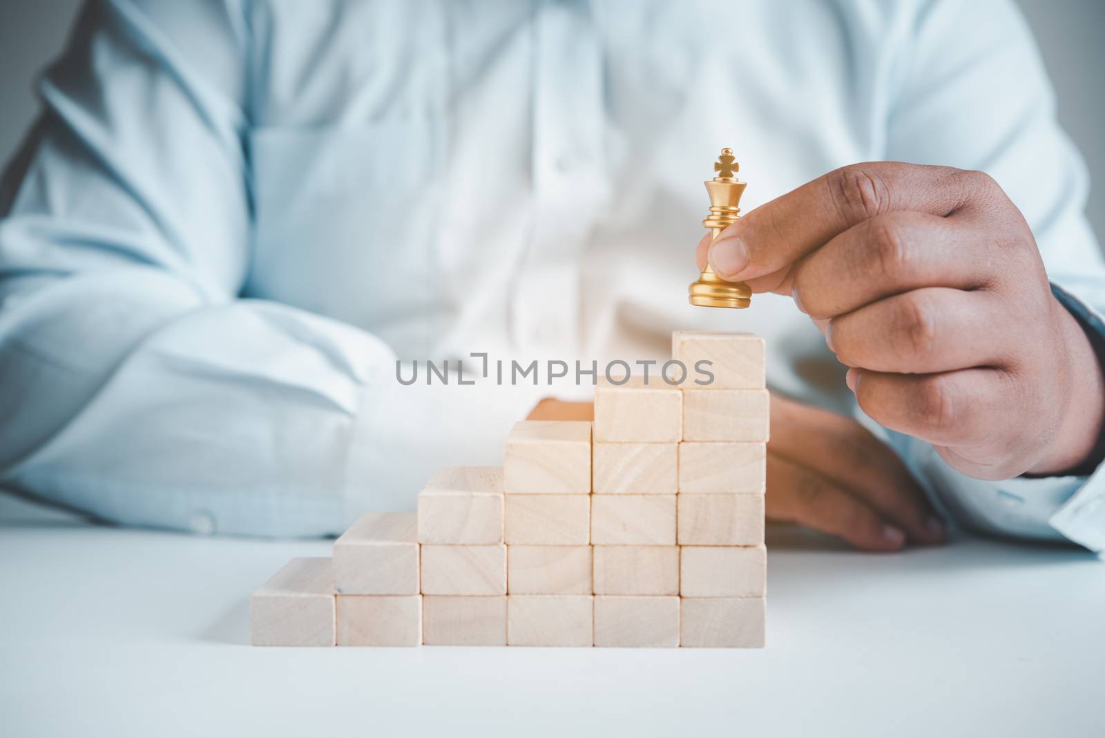 Businessman's hand picks up chess on a wooden block, concept lea by photobyphotoboy