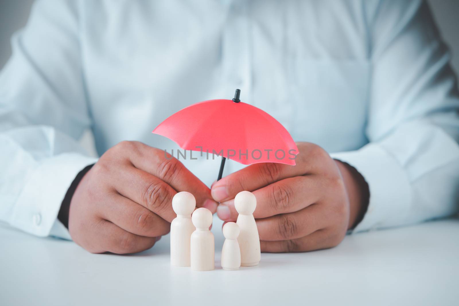 businessman's hand is holding an umbrella on the family tree. Businesses in human life, both health and family life.