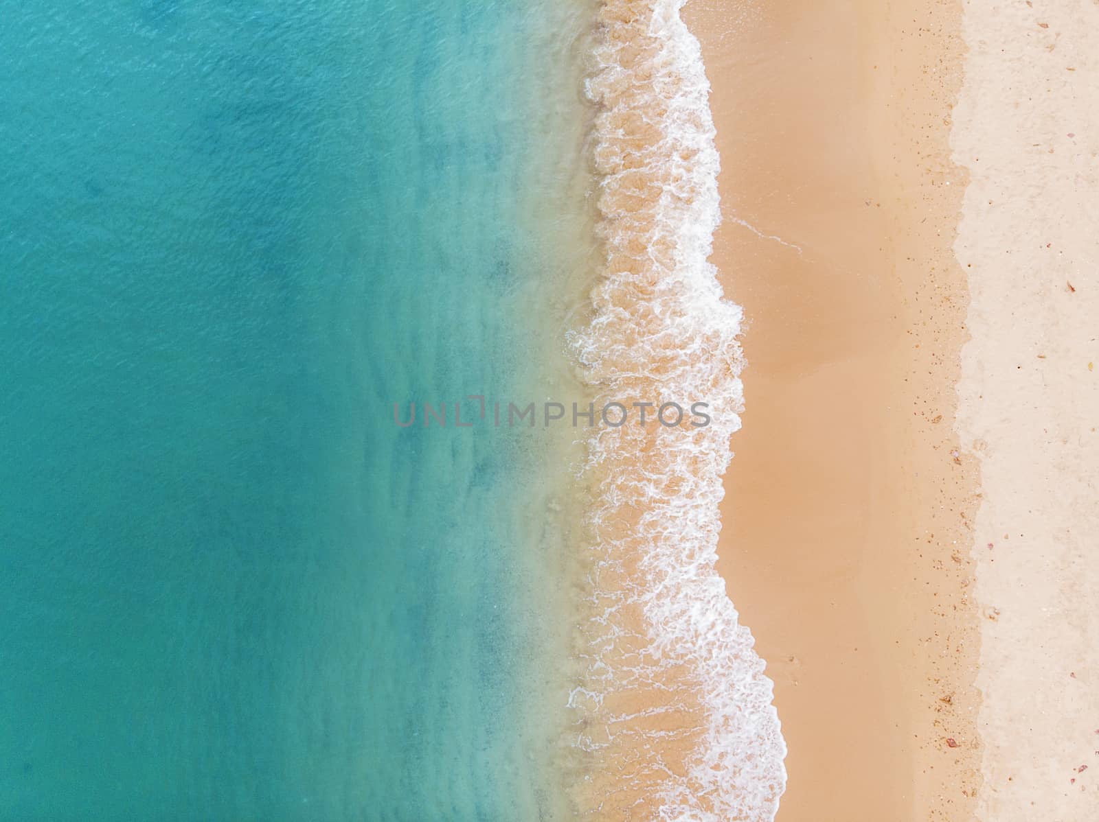Aerial view of beach and blue ocean with waves reaching shore