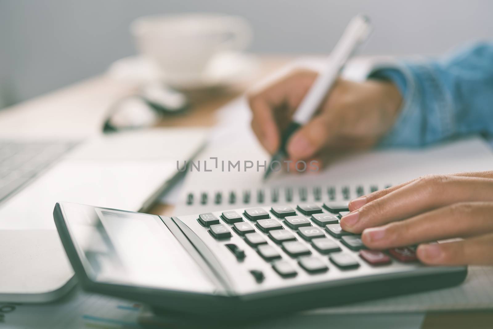 The accountant's hand is using the calculator. For cost analysis by photobyphotoboy