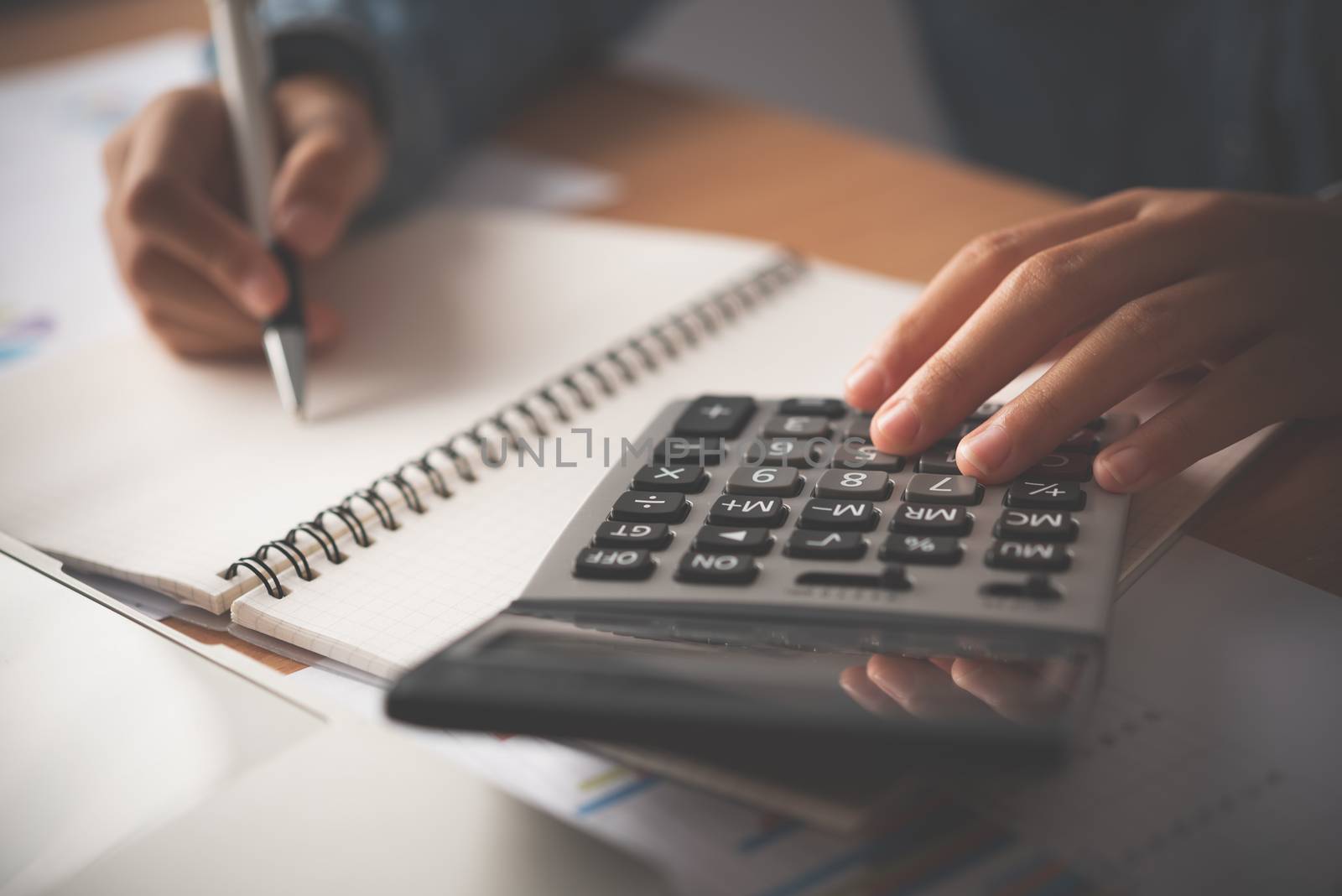 The accountant's hand is using the calculator. For cost analysis by photobyphotoboy