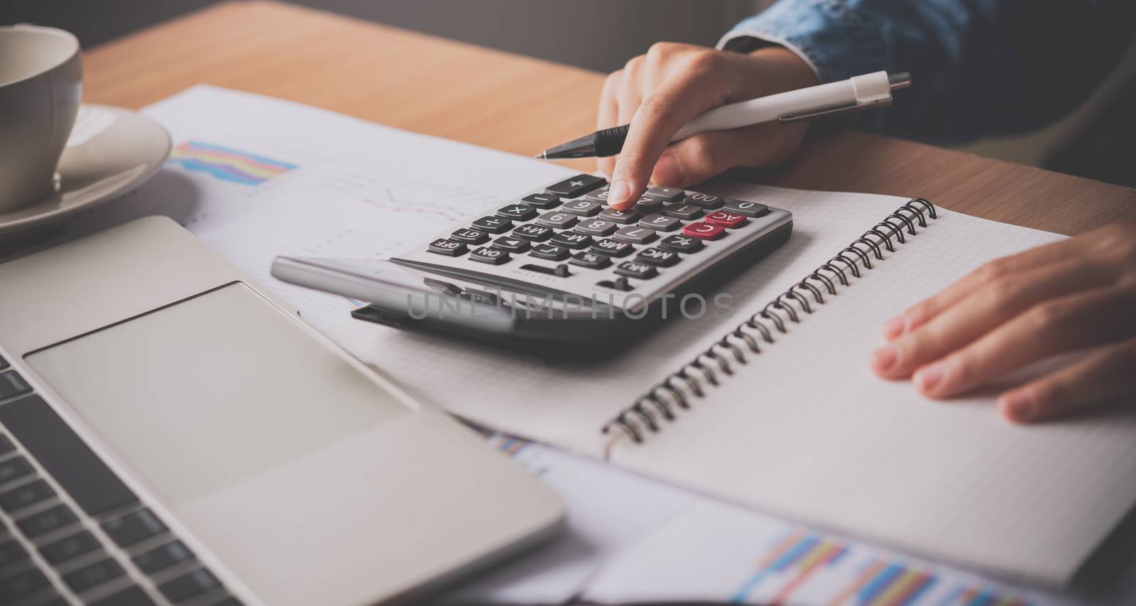 The accountant's hand is using the calculator. For cost analysis by photobyphotoboy