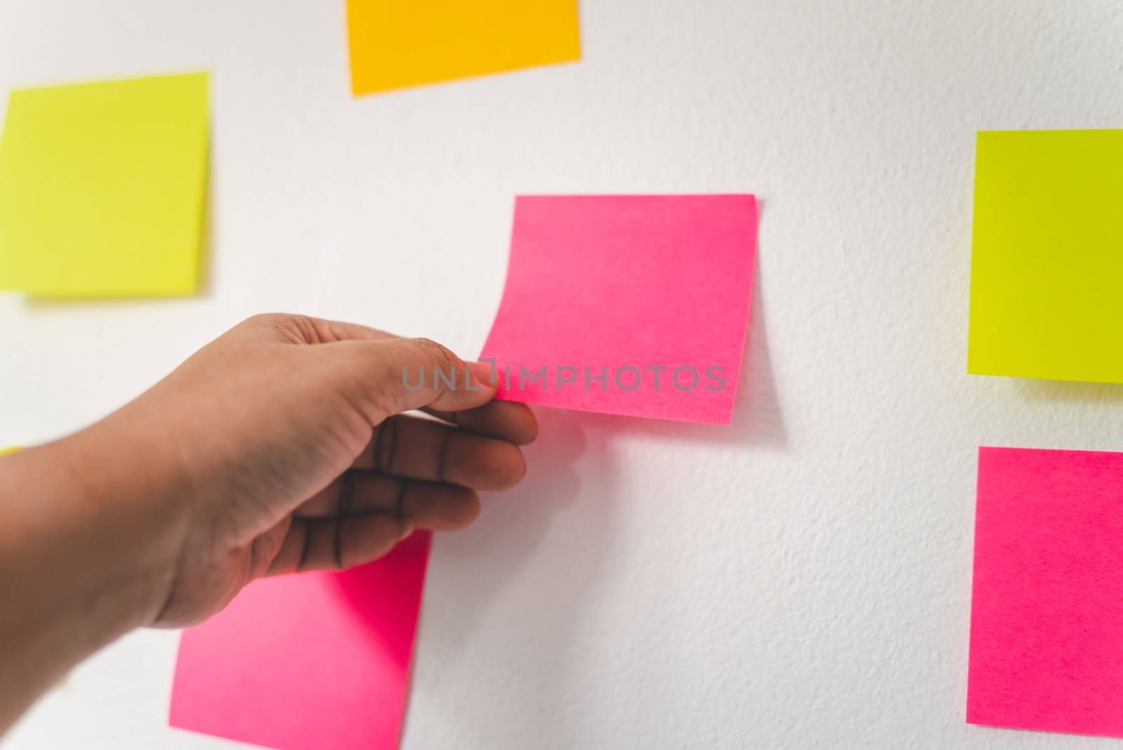 The hand is holding the post it notes attached to the wall. Conc by photobyphotoboy