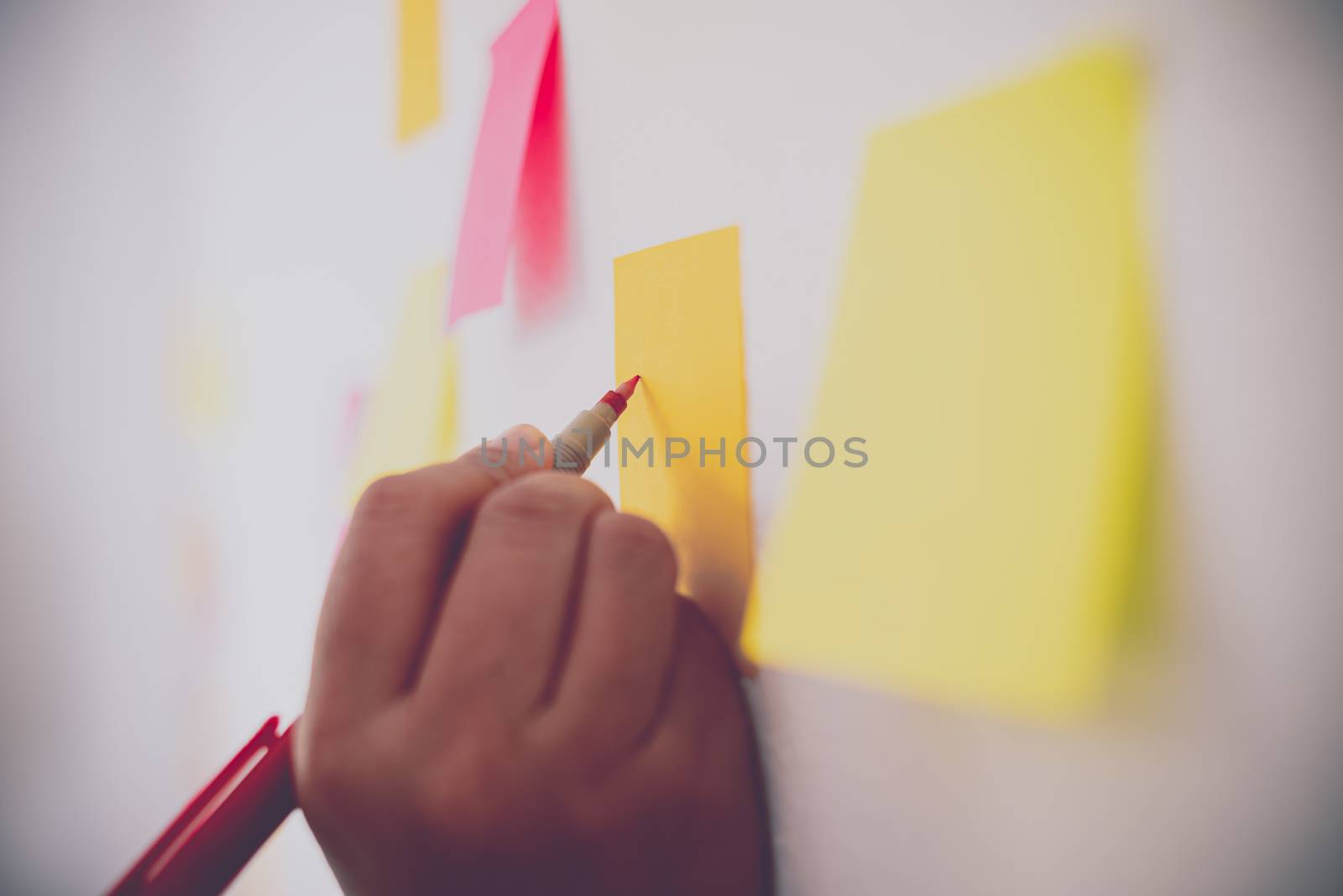 The hand is holding the post it notes attached to the wall. Conc by photobyphotoboy