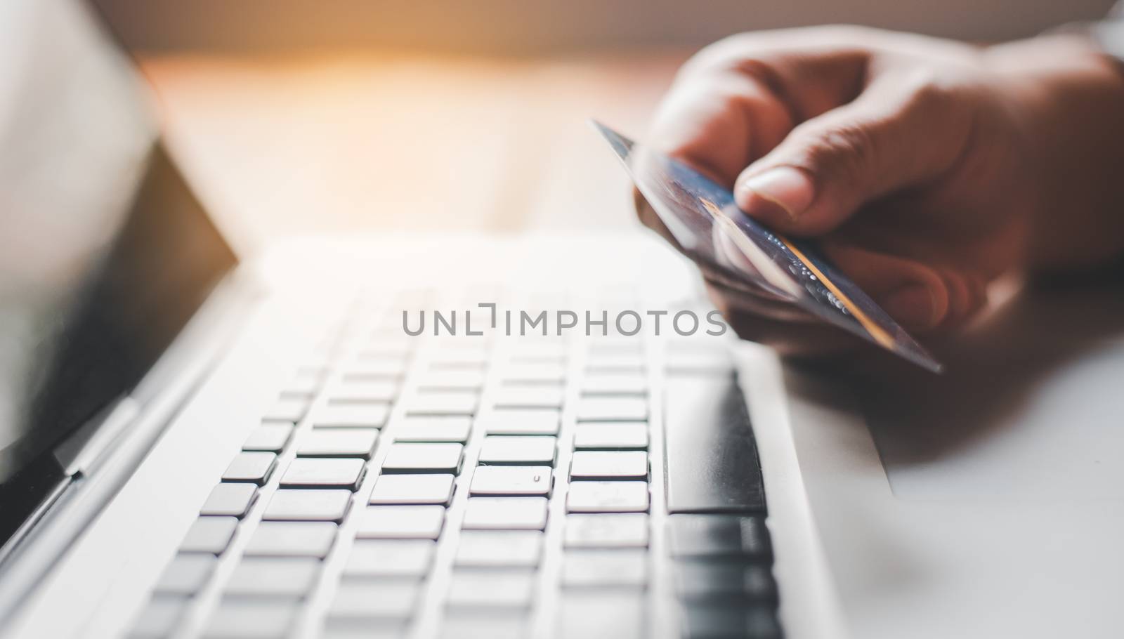 Hand holding a credit card in their hands and find information about a product using their mobile device to make purchases online and conduct financial transactions.