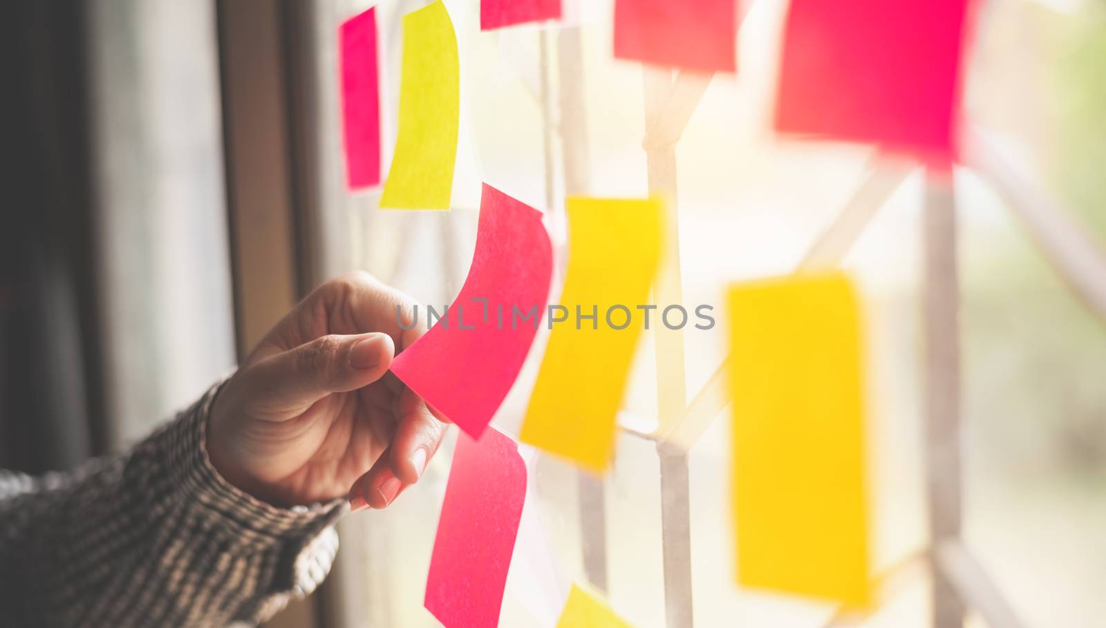 hand is holding the post it notes attached to the glass wall. Co by photobyphotoboy