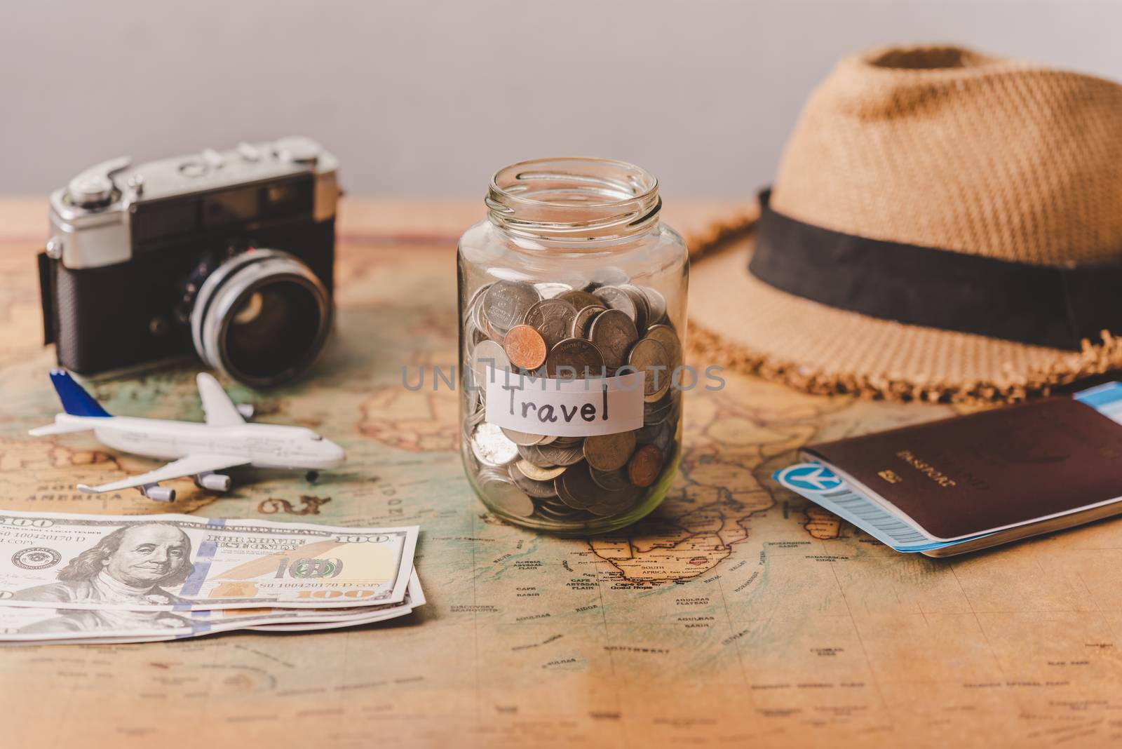 The money in the jar stored on the map, along with a passport, concept to collect money for travel.