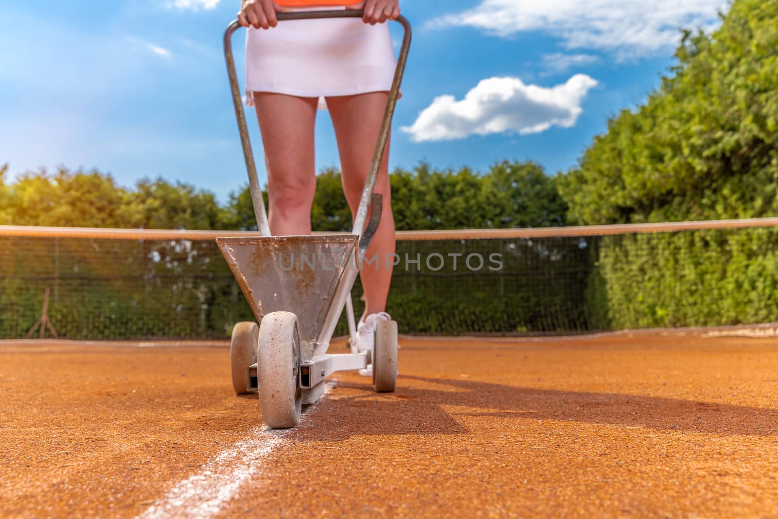 tennis player marks a lime white line on a tennis court. copy space.