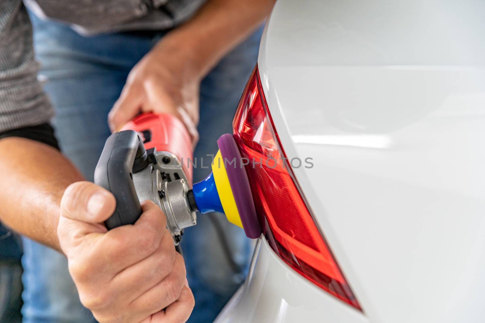 hand polishing car headlights with the help of a hand grinder for better shine.