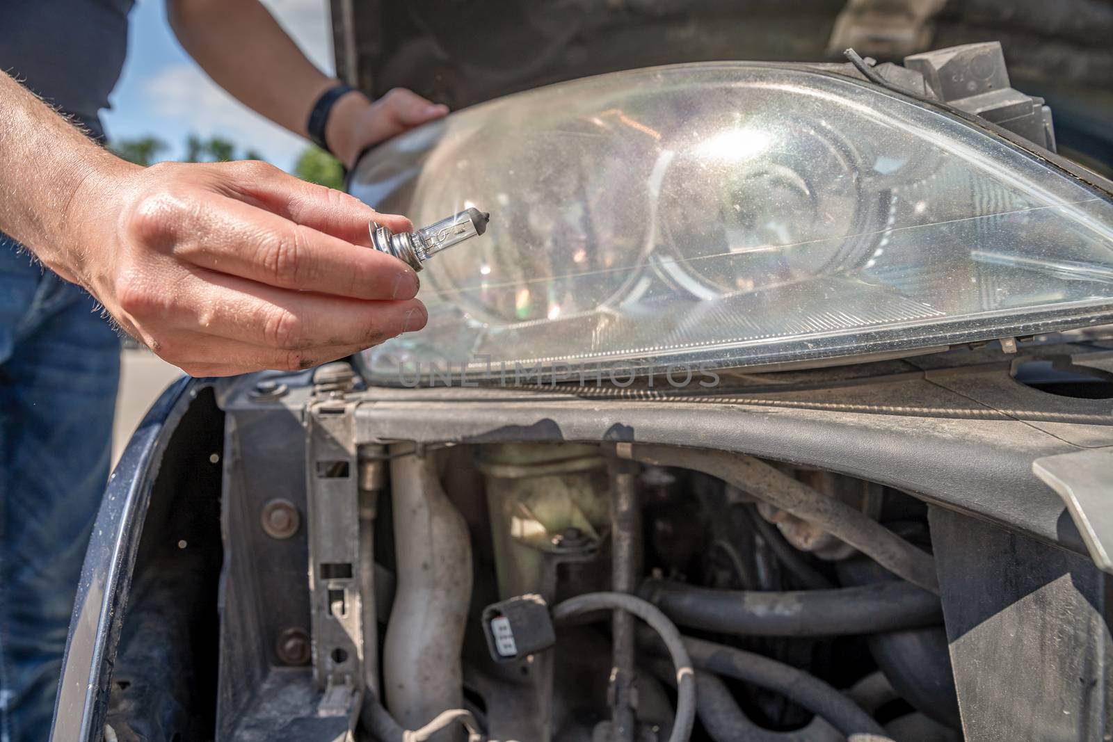 The man changes the bulb in the headlight of a car by Edophoto