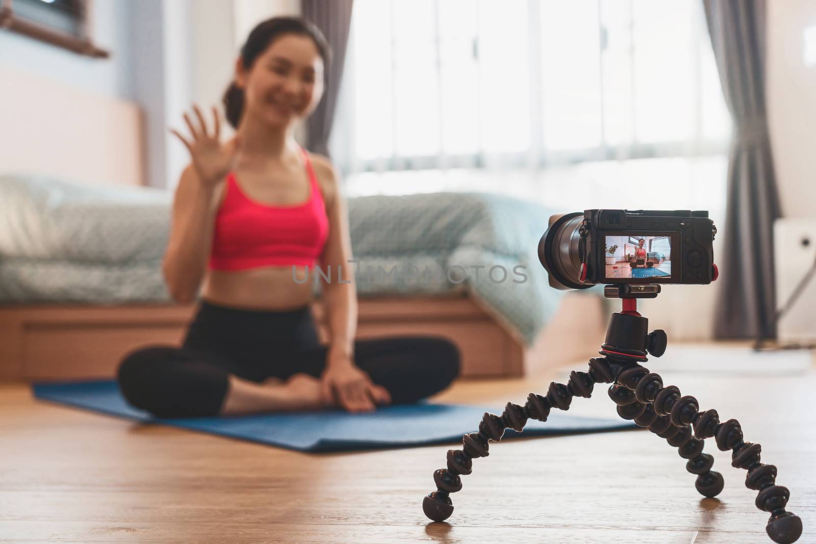 Camera taking video and live of Asian woman practicing yoga from home in bedroom when Covid19 outbreak, healthy or Meditation Exercise, coronavirus pandemic and quarantine,vlog and Influencer concept