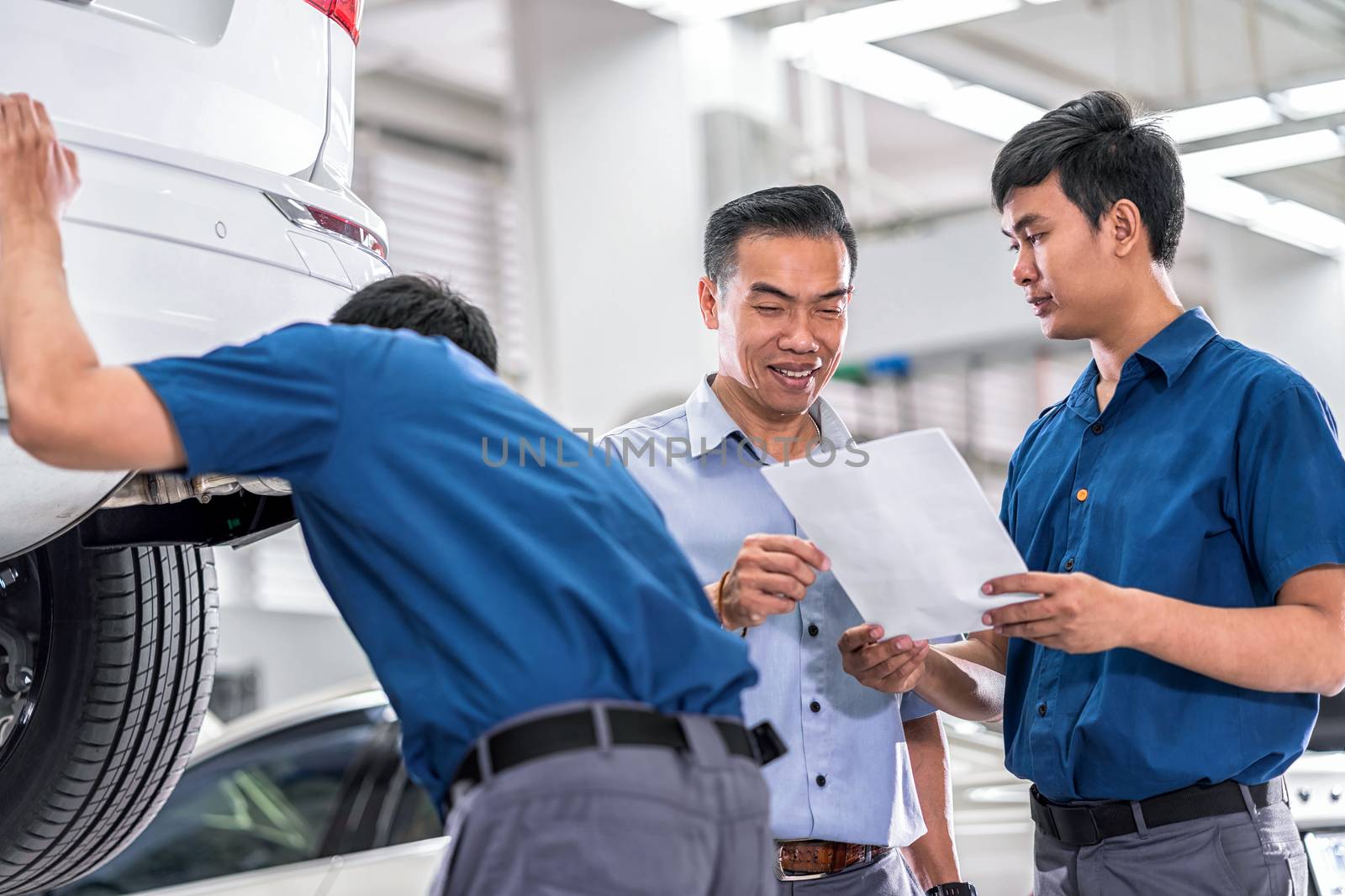 Asian Mechanic talking and showing job to the customer about repair service in maintenance service center which is a part of showroom, car repair and agreement on the job concept,