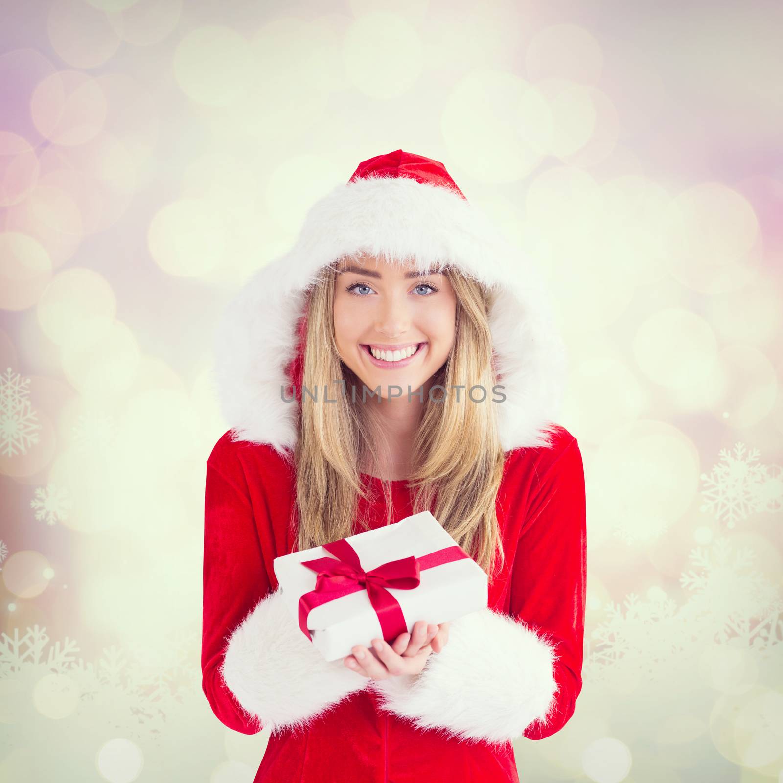 Sexy santa girl holding gift against glowing christmas background