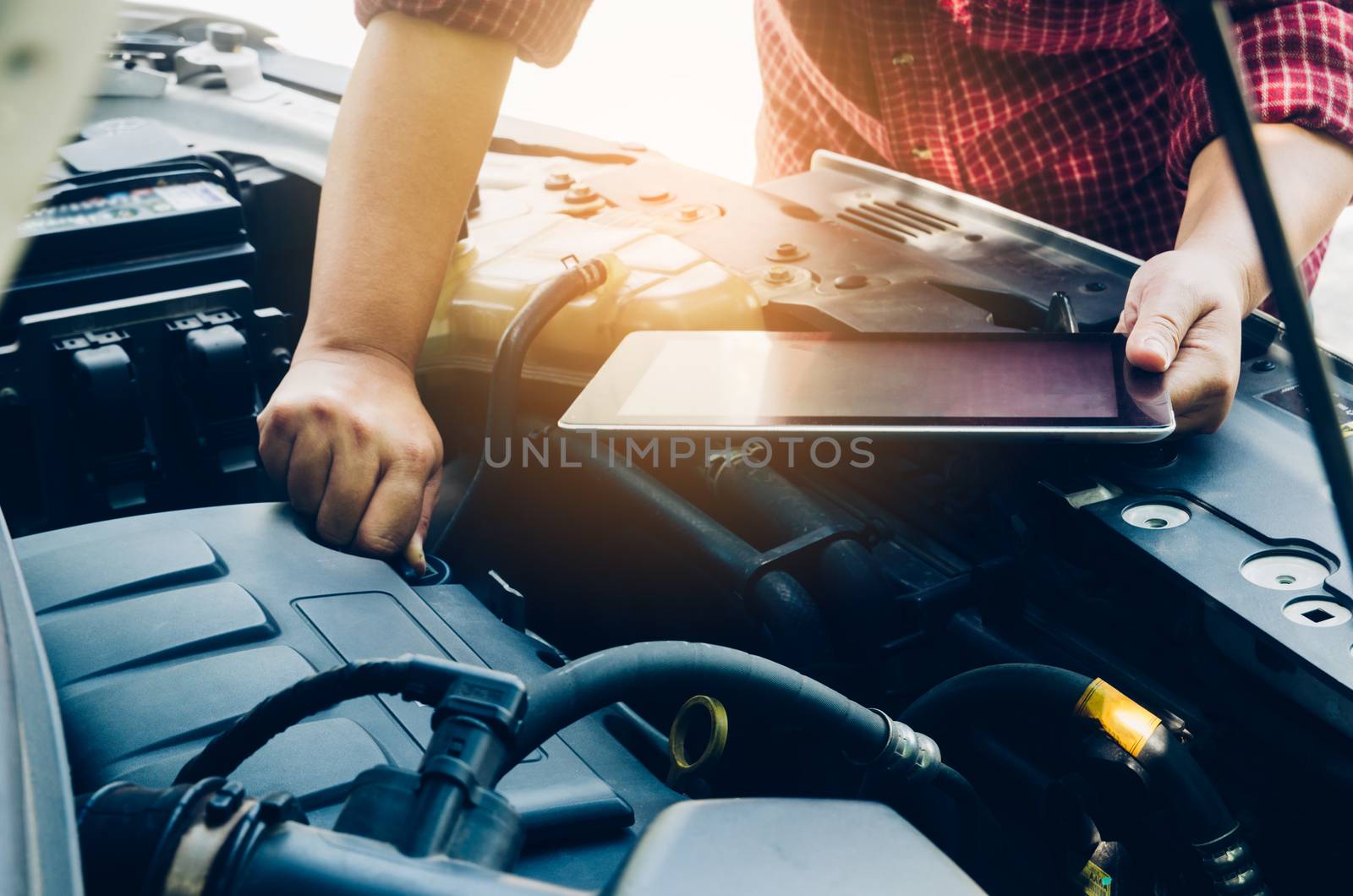 Man checking on a car engine and hold tablet search for data by photobyphotoboy