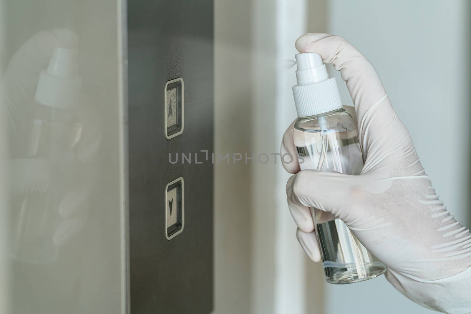 Closeup Asian woman hand wearing medical gloves and spraying Anti-Bacterial Sanitizer Spray to the elevator button before cleaning press, Coronavirus Network Outbreak, health care and cleaning covid19