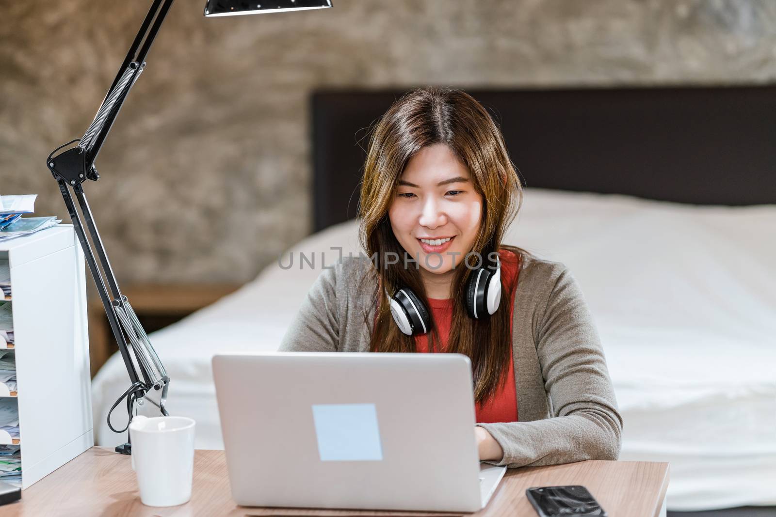 Asian business woman using technology laptop and working from home in indoor bedroom,freelance and entrepreneur,startups and business owner,lifestyle occupation,social distance and self responsibility