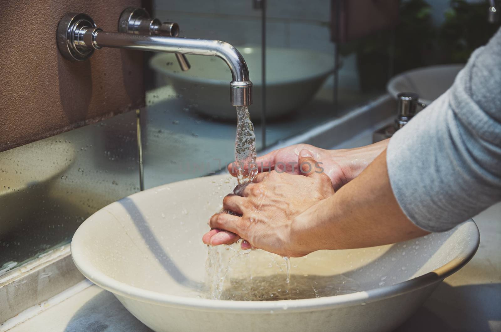 Closeup hands washing with Chrome faucet and water for Coronavirus pandemic prevention in bathroom, self responsibility cleaning, hand hygiene corona virus protection concept