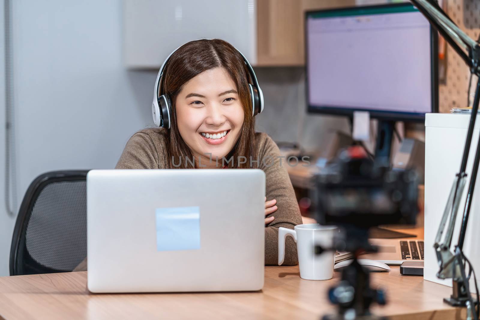 Asian business woman using technology laptop and working from home in home offuce, freelance and entrepreneur, camera taking video of vlooger or influence Live, social distance and self responsibility