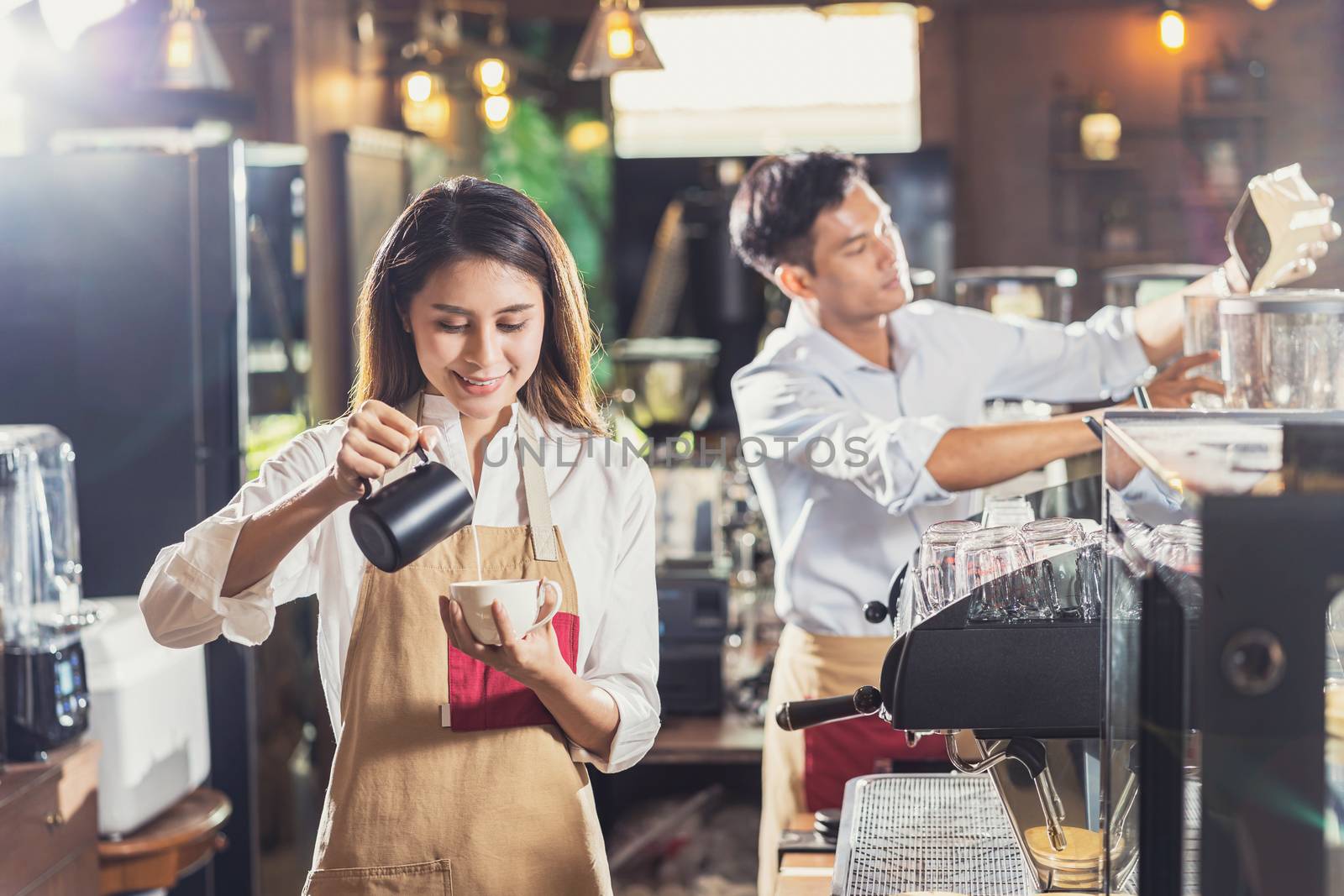 Asian Barista preparing cup of coffee, espresso with latte or cappuccino for customer order in coffee shop,bartender pouring milk,Small business owner and startup in coffee shop and restaurant concept