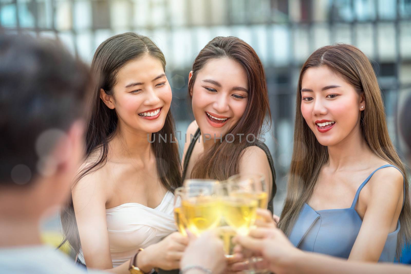 Happiness Asian Girl Friend Group celebrating and Cheering together with glass of wine at sunset time on rooftop of downtown hotel or nightclub,hens night,holiday, or yearly anniversary party concept