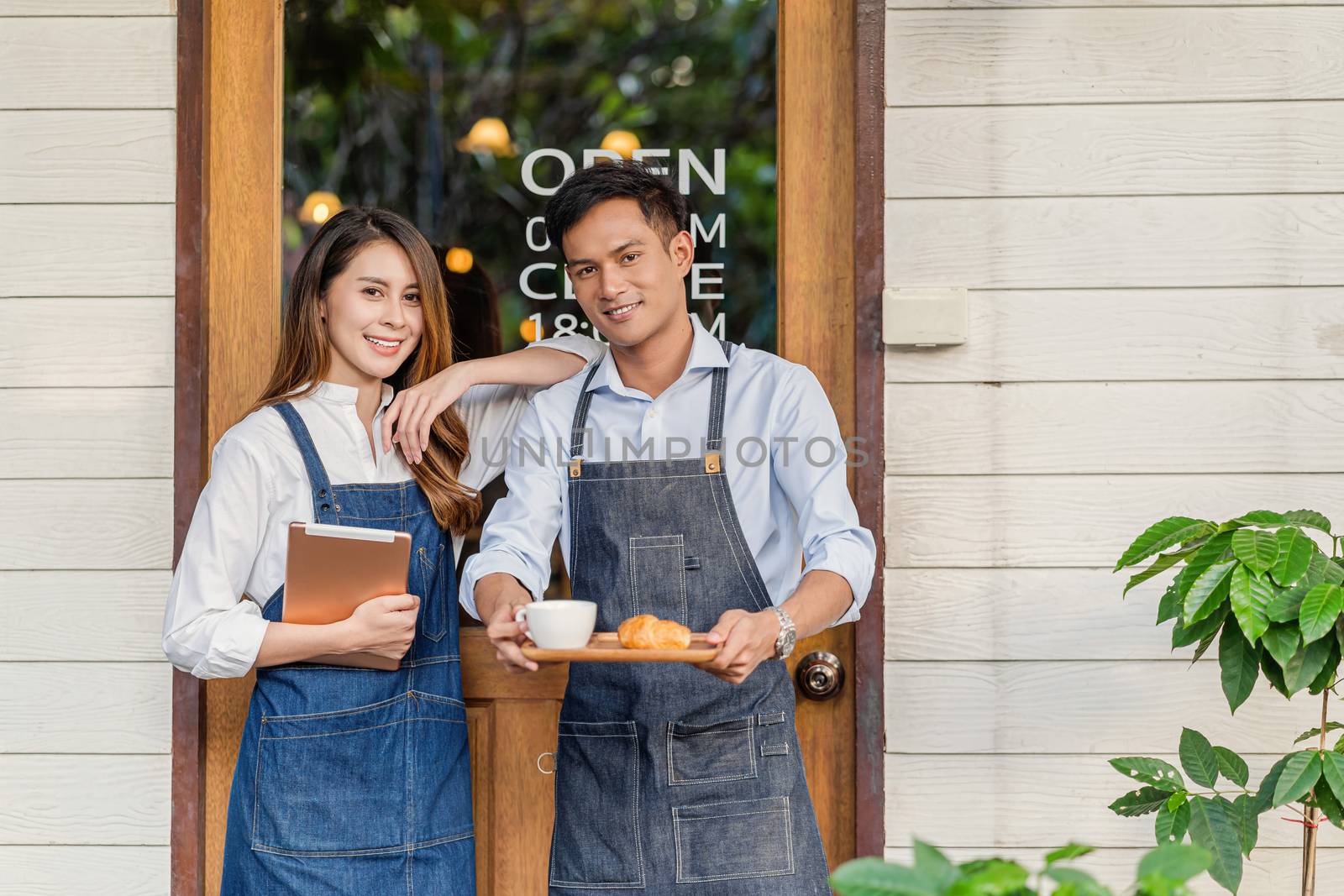 Asian partner Small business owner hands holding coffee cup with bakery Croissant showing serv to customer in front of coffee shop, startup with cafe store, installing open and close label concept