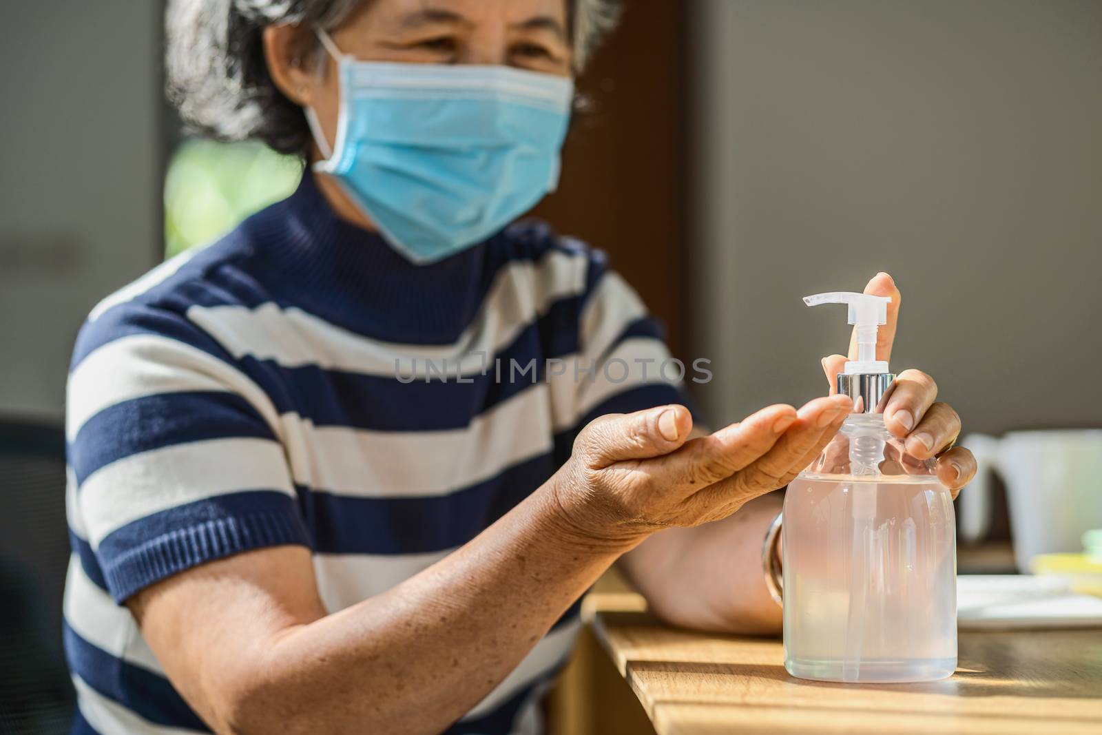 Closeup Asian old man woman using hand sanitizer by pumping alcohol gel and washing before working in work from home period,coronavirus or covid19 outbreak,social distancing and responsibility