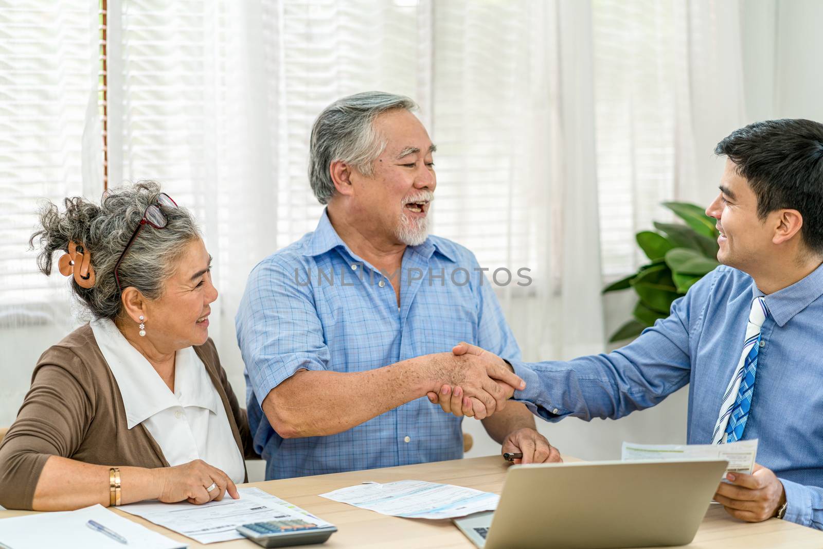 Insurance agency manager handshake with Asian couple grandparent in happy feeling after deal the agreement successful,financial planner presenting and Closing the sale of real estate,document and bill
