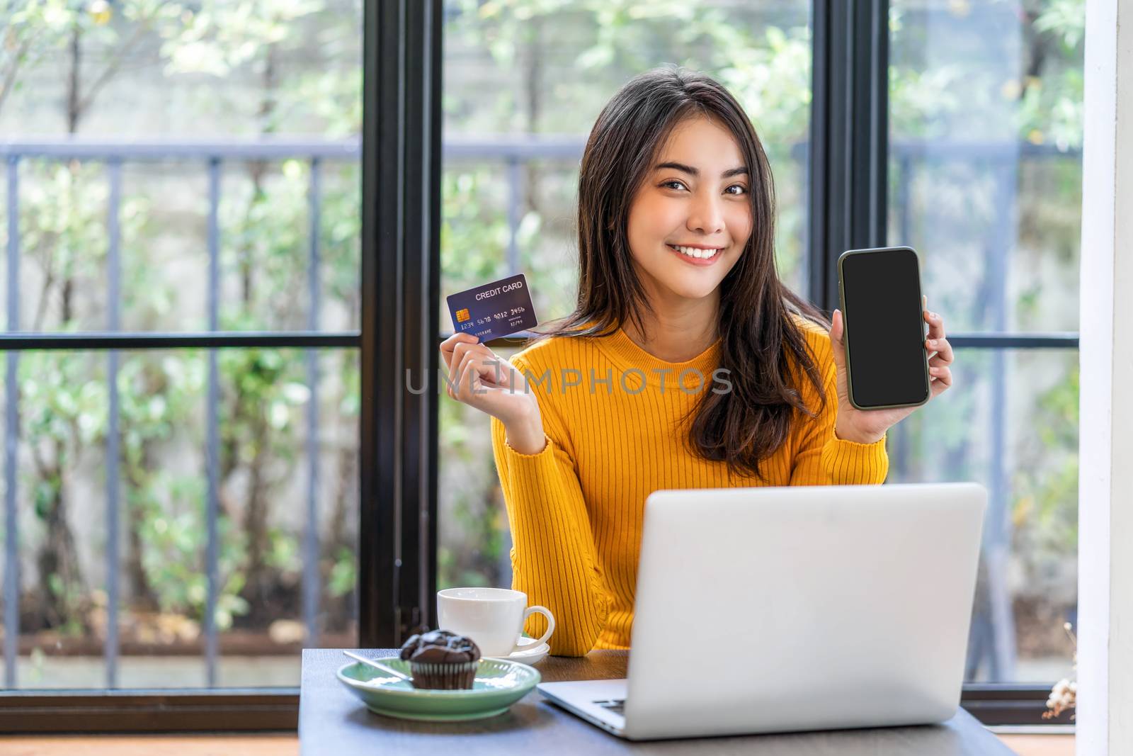 Young Asian woman using credit card and presenting mobile phone  by Tzido