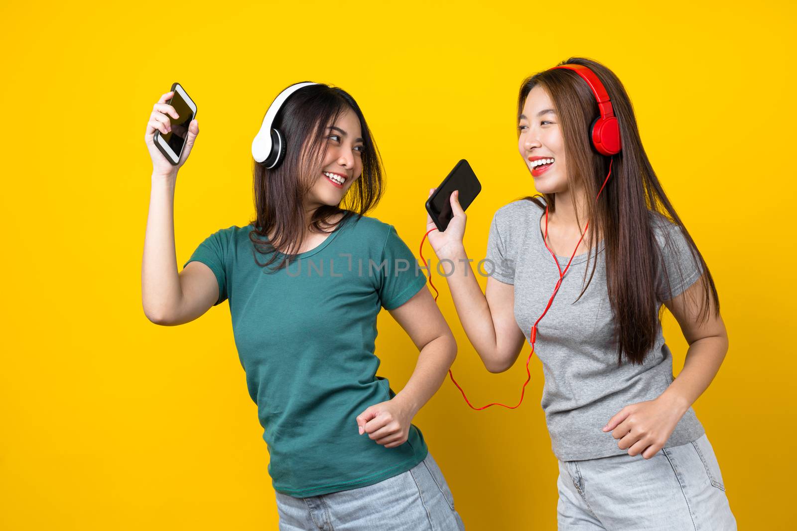 Two Happiness Asian smiling young woman wearing wireless headpho by Tzido