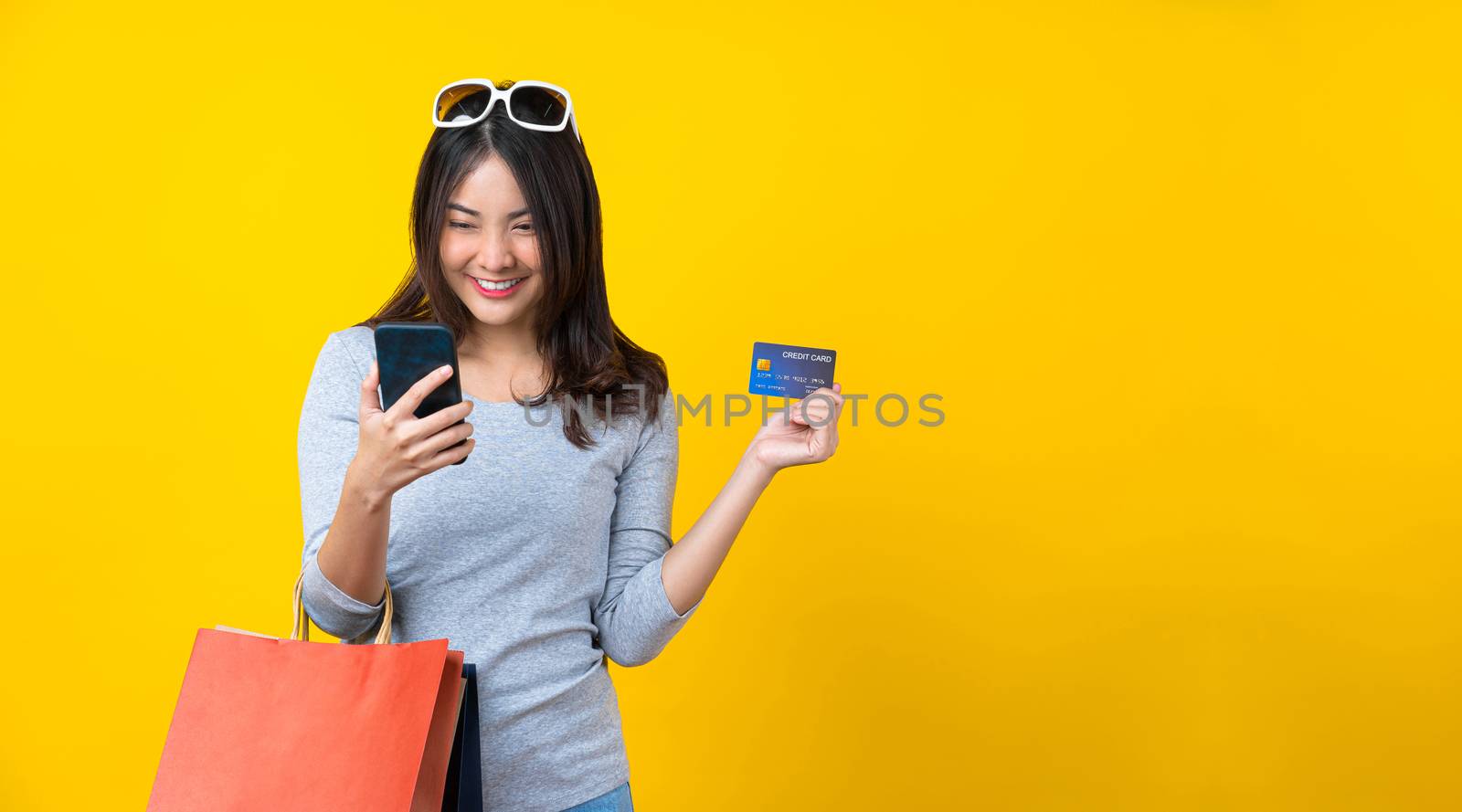 Happy Asian smiling woman using mobile phone and credit card and by Tzido