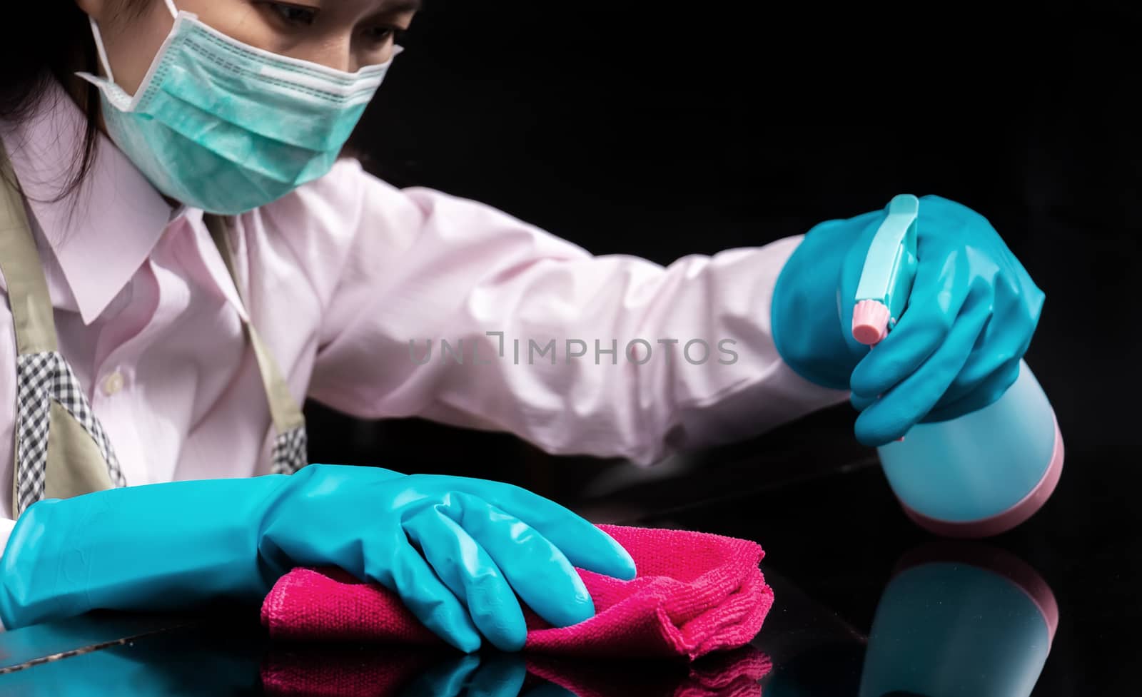 woman wear a hygienic mask , use blue rubber glove holding pink microfiber cleaning cloth and spray bottle with sterilizing solution make cleaning and disinfected for good hygiene