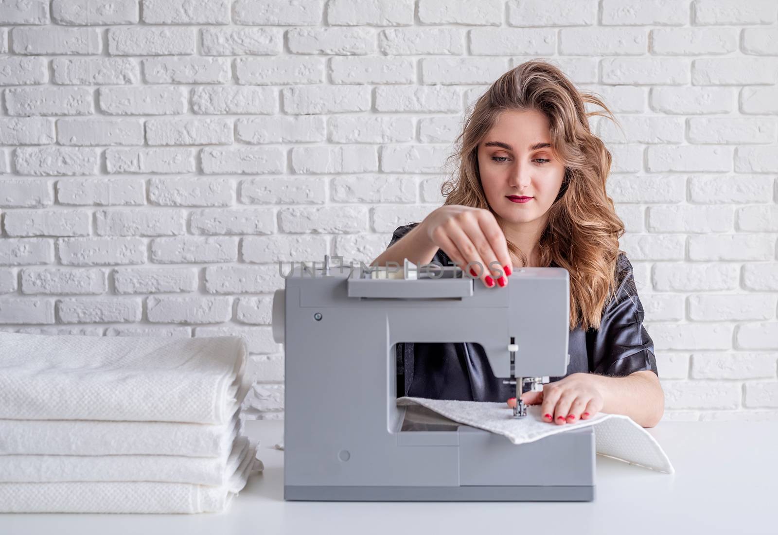 Beautiful housewife sewing towels at home using a sewing machine