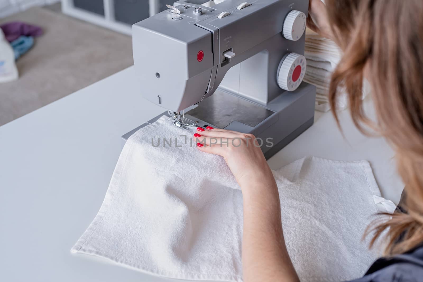 Beautiful housewife sewing towels at home using a sewing machine