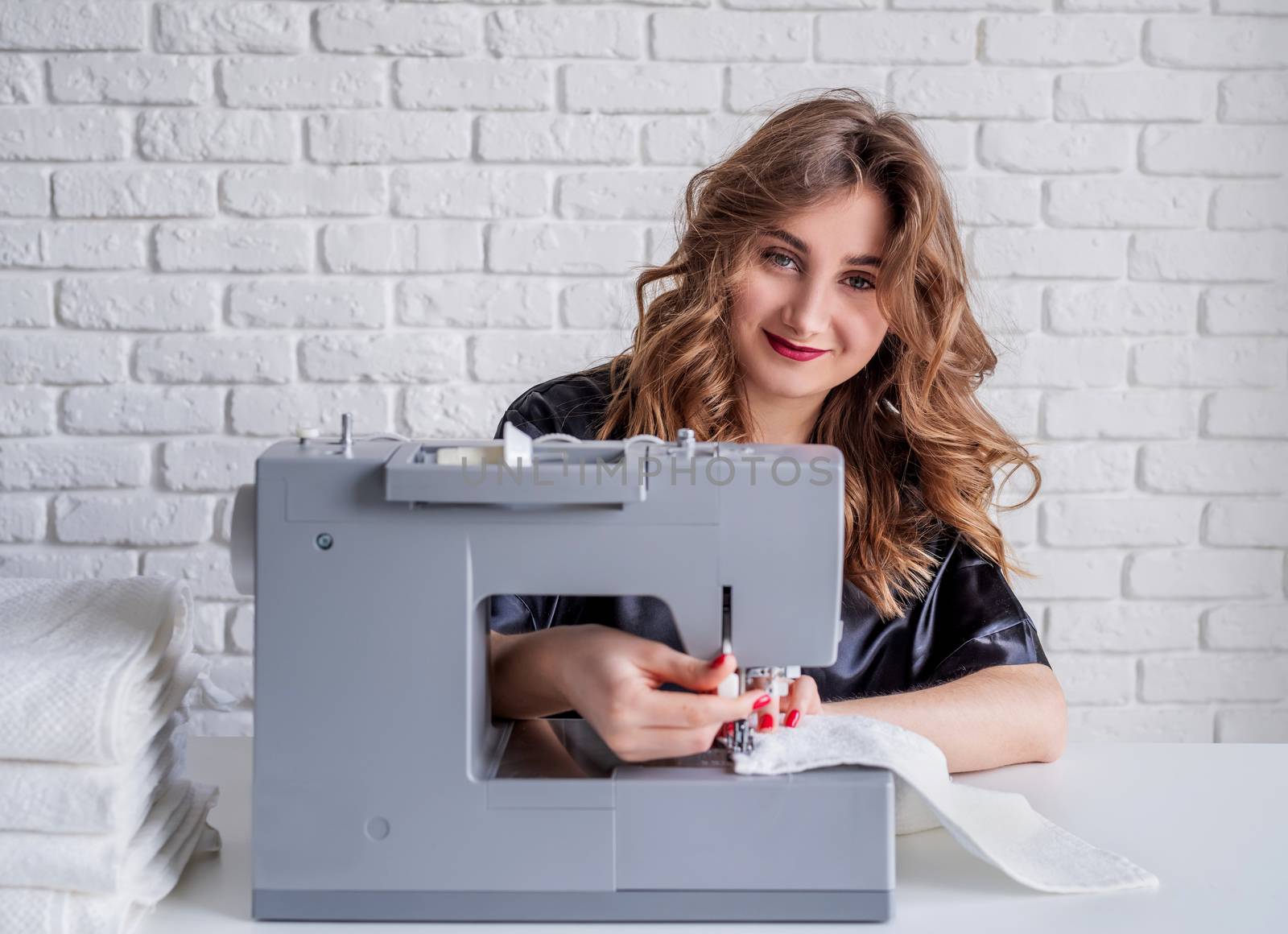 Beautiful housewife sewing towels at home using a sewing machine