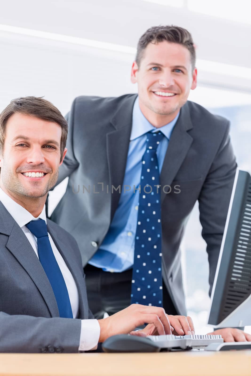 Portrait of smartly dressed young businessmen using computer at office desk