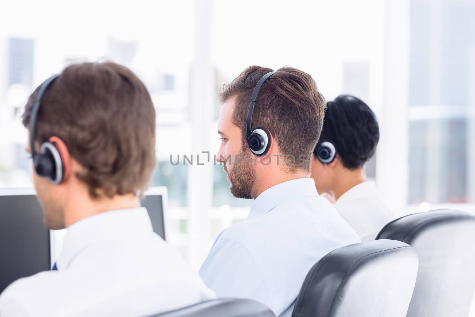 Rear view of a group of business colleagues with headsets in row at office