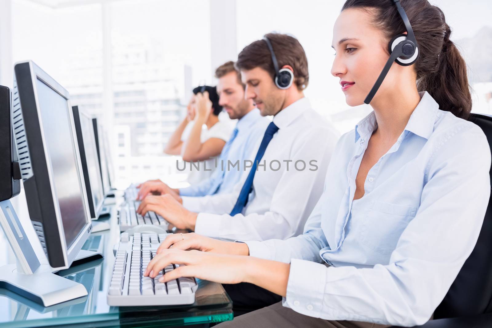 Business colleagues with headsets using computers by Wavebreakmedia