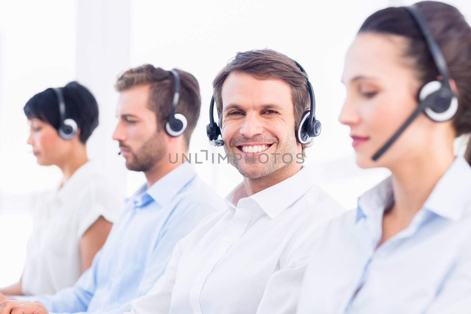 Business colleagues with headsets in a row by Wavebreakmedia