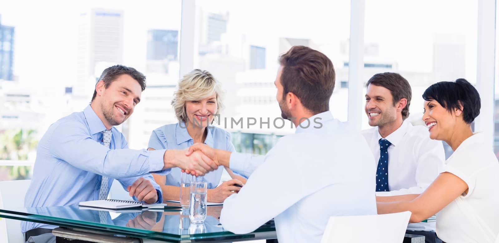 Executives shaking hands during business meeting at office desk