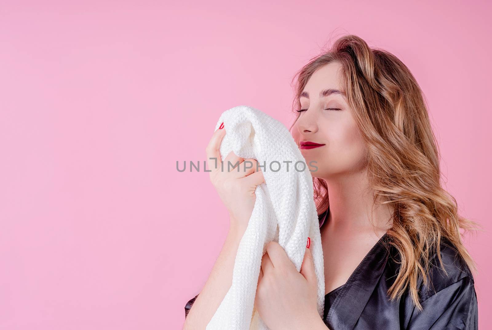 Laundry concept. Beautiful woman smelling clean clothes isolated on pink background with copy space