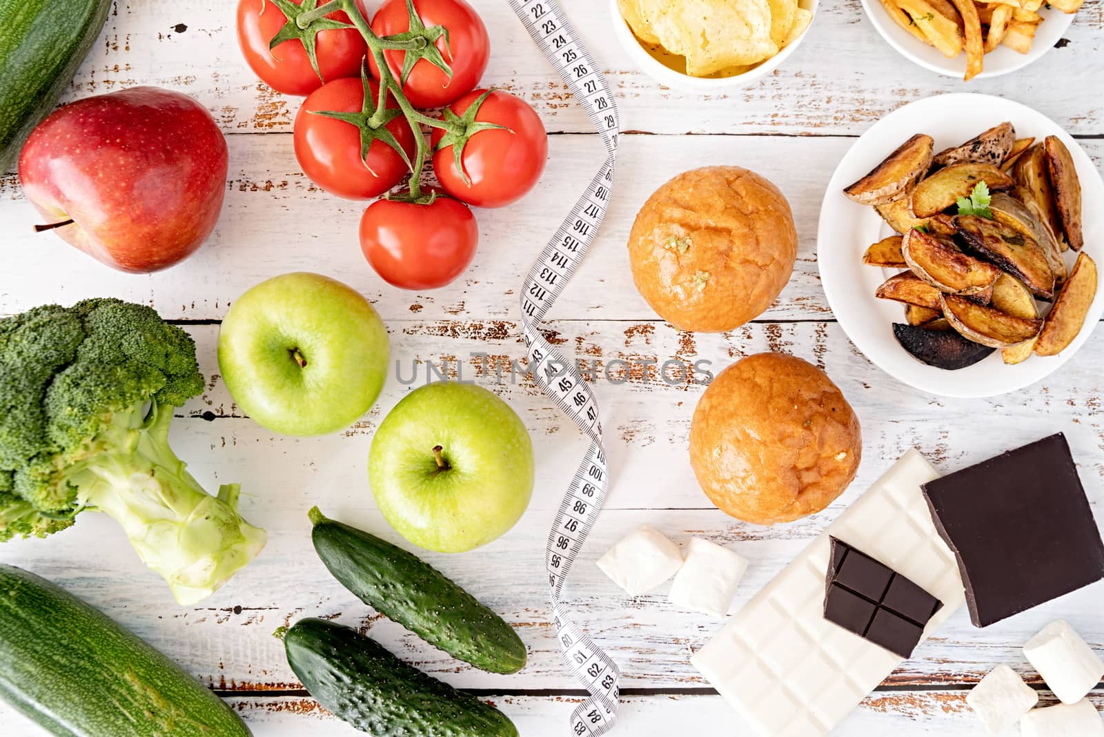 Healthy and unhealthy food concept. Fruit and vegetables vs sweets, burgers and potatoe fries top view flat lay on white rustic background