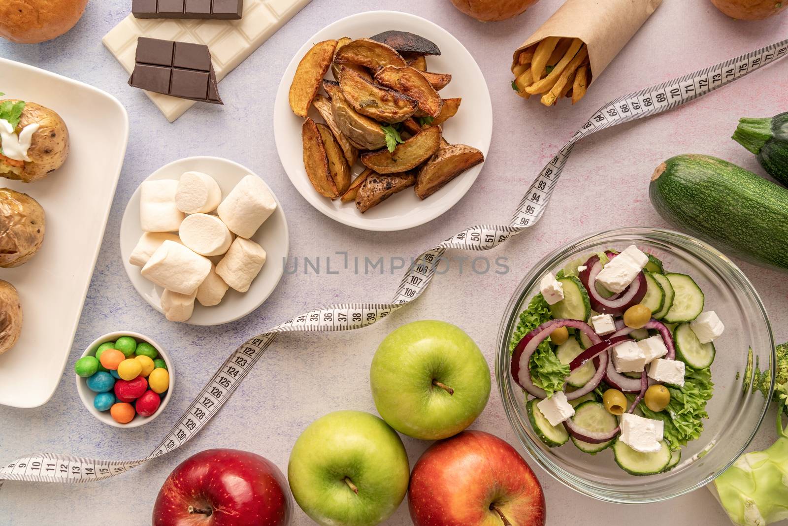 Healthy and unhealthy food concept. Fruit and vegetables vs sweets and potato fries top view flat lay with a measuring tape